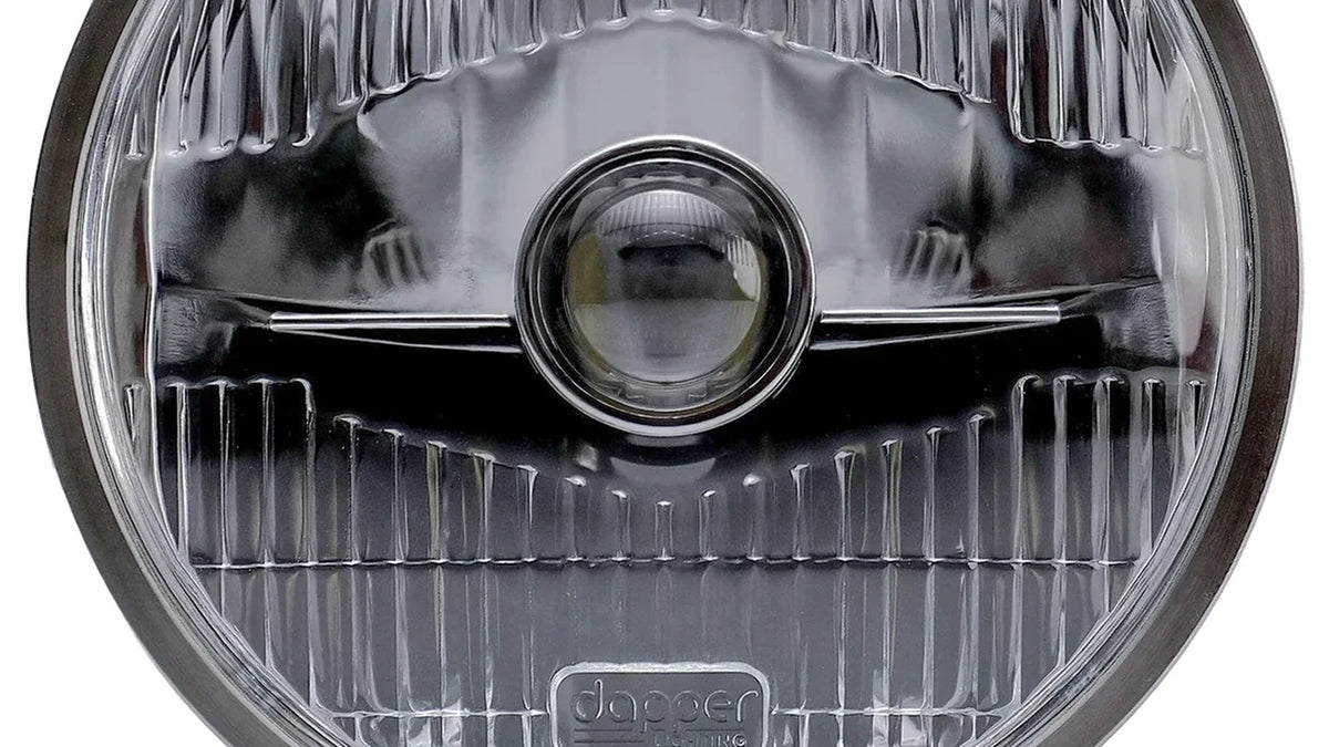 Close-up of an OE7 headlight showing its glass lens and central projector.