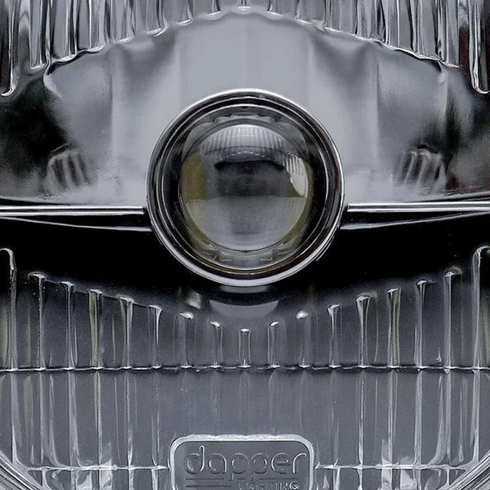 Close-up of an OE7 headlight showing its glass lens and central projector.